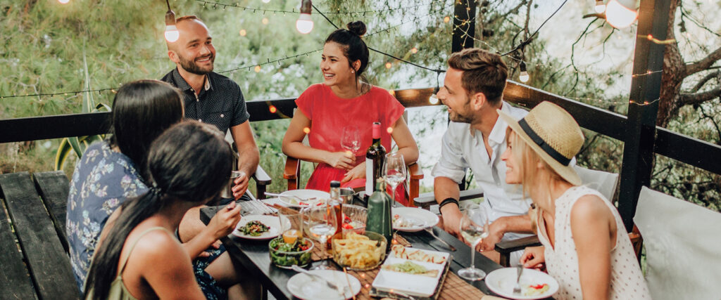 Personen sitzen draußen und essen gemeinsam