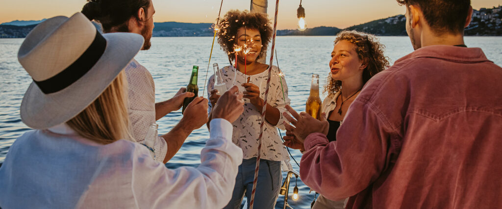 Personen stoßen am Meer in der Abenddämmerung gemeinsam an