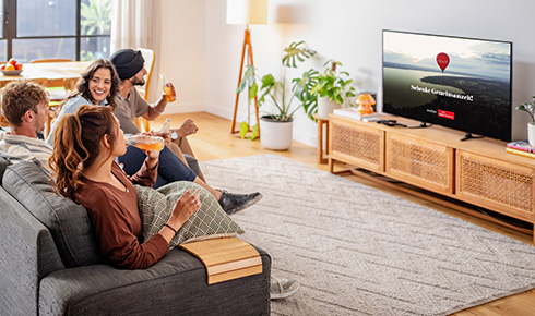 Personen sitzen auf dem Sofa vorm Fernseher auf dem der Co-Branded Werbespot von Cewe und mydays läuft