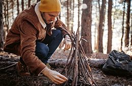 Mann der im Wald ein Lagerfeuer vorbereitet