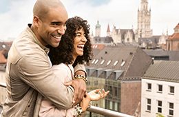 Pärchen auf einem Balkon mit Stadt im Hintergrund
